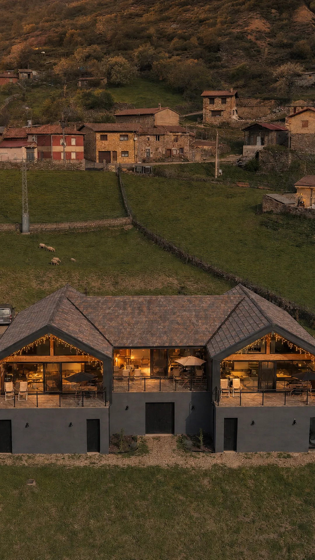 Las tres casas rurales iluminadas al atardecer frente al pueblo