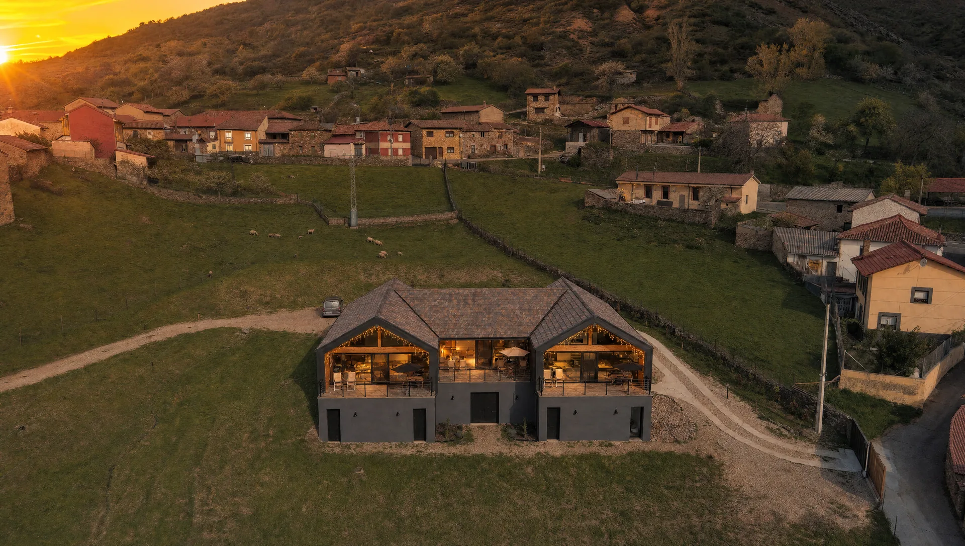 Las tres casas rurales iluminadas al atardecer frente al pueblo